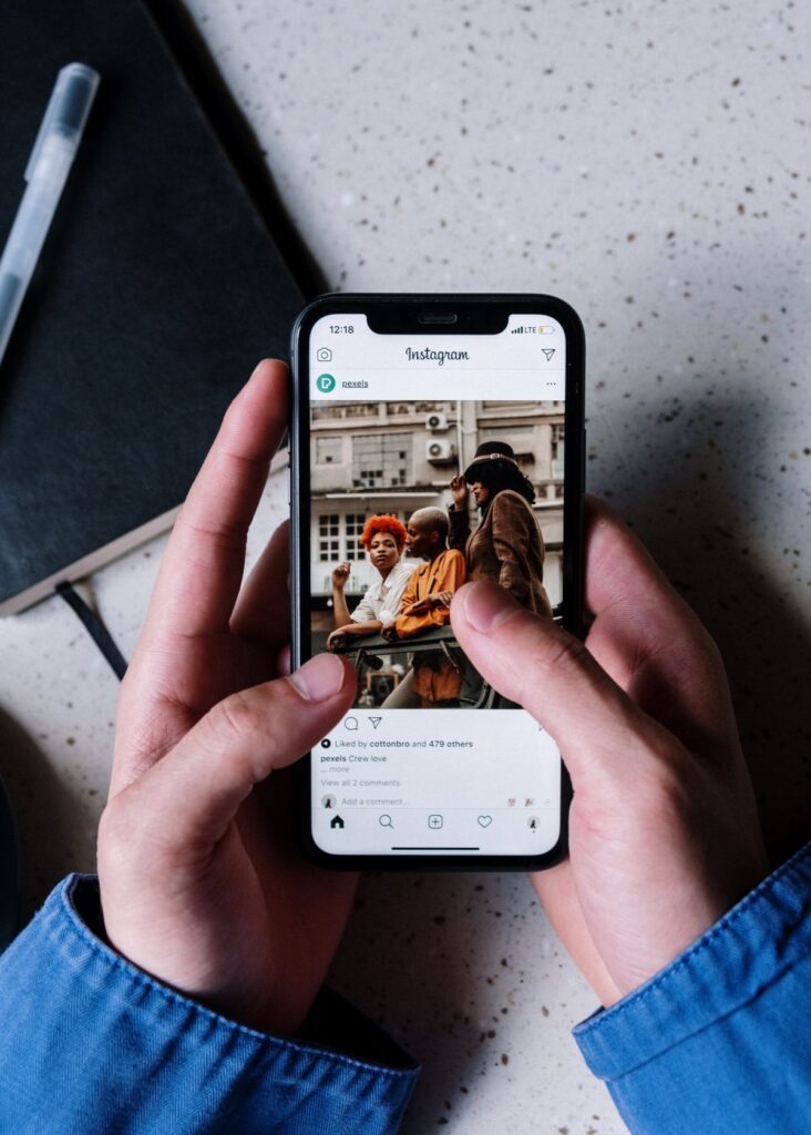 Tangan memegang smartphone menampilkan postingan Instagram