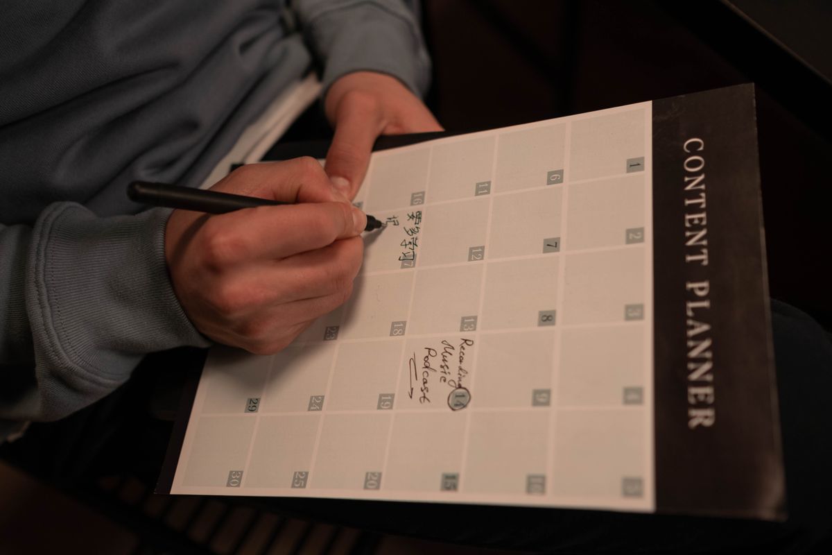 Tangan menjadwalkan konten di kalender content planner bulanan