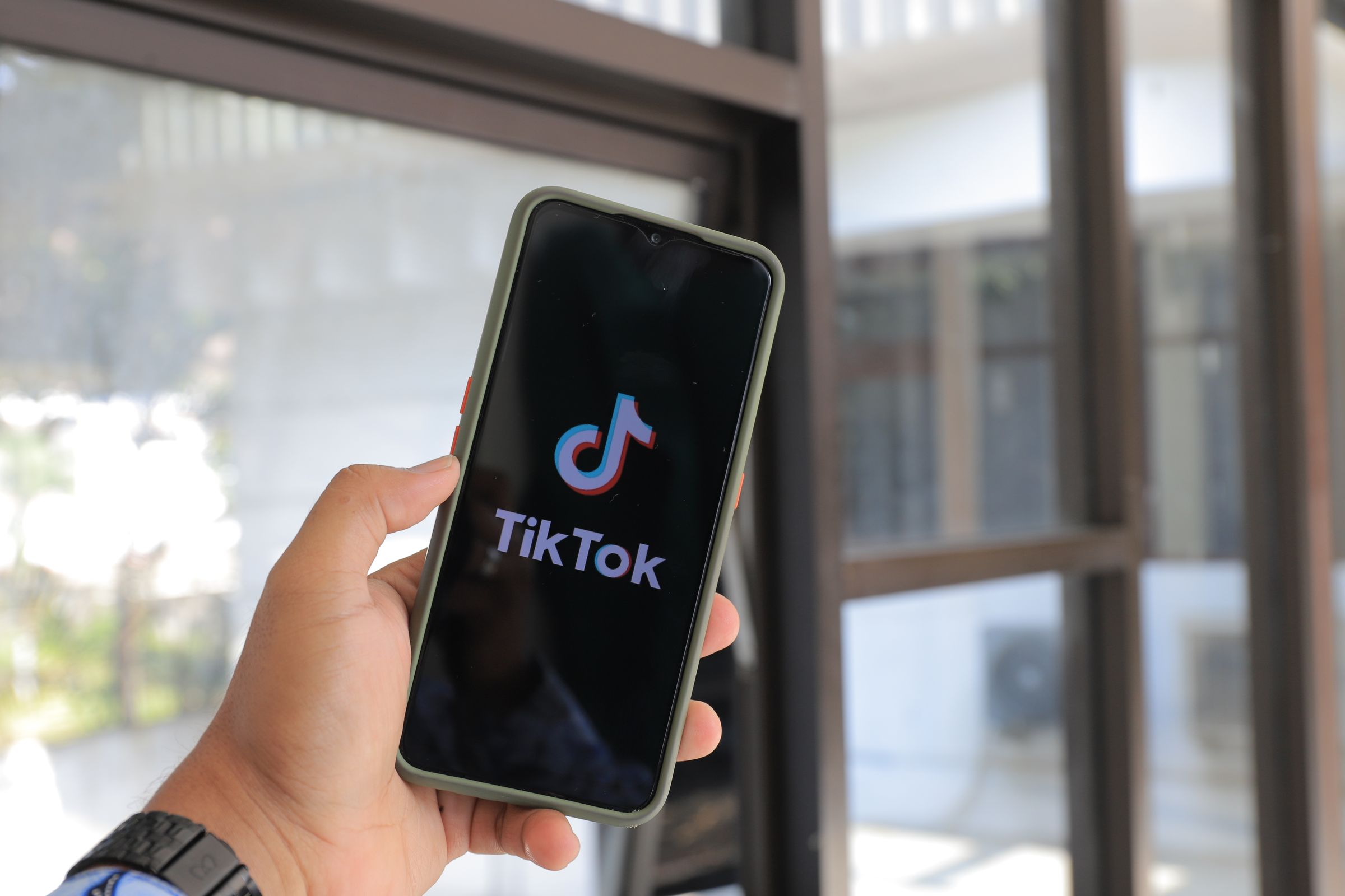 Tangan memegang smartphone yang membuka aplikasi TikTok